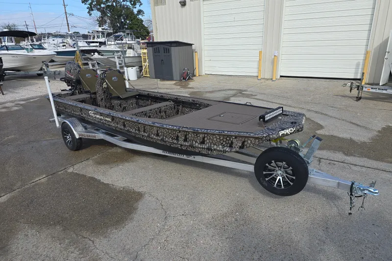 Slide: The Image of 2026 Pro-Drive 2060 boat on trailer, camo design, parked near storage facility. - 3
