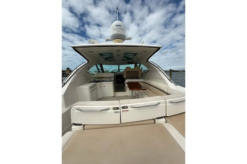 Slide: The Image of 2014 Sea Ray 470 Sundancer yacht interior with seating and table under a cloudy sky. - 11