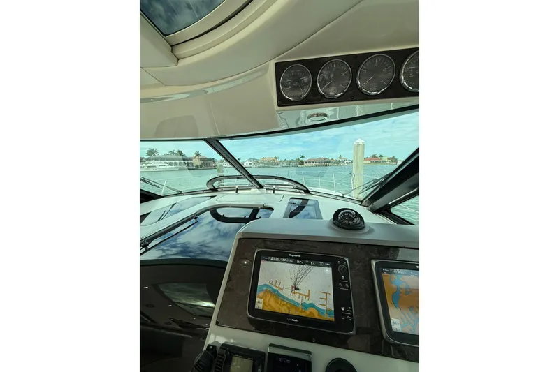 Slide: The Image of 2014 Sea Ray 470 Sundancer cockpit with navigation screens and waterfront view. - 35