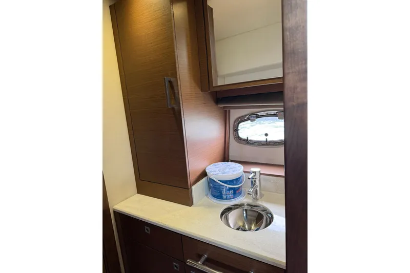 Slide: The Image of 2014 Sea Ray 470 Sundancer bathroom with sink, cabinet, and porthole window. - 85