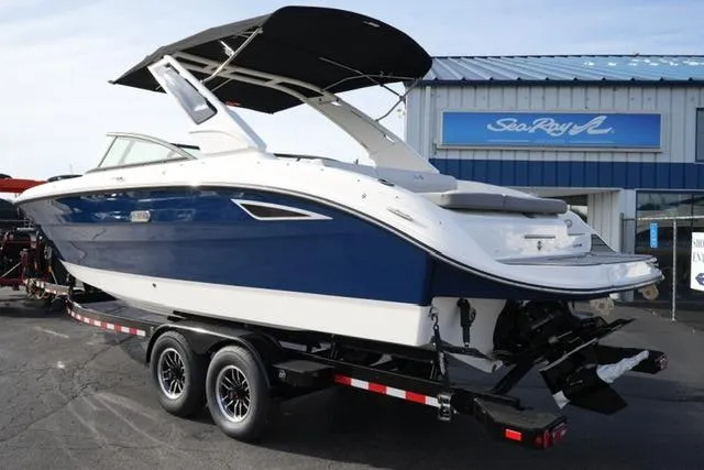 Slide: The Image of 2025 Sea Ray SDX 270 boat on trailer, blue and white design, outside dealership. - 7