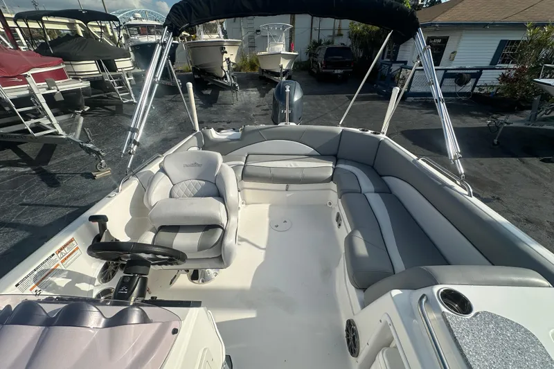Slide: The Image of 2022 NauticStar 203 SC boat interior with seating and steering wheel, docked outdoors. - 16