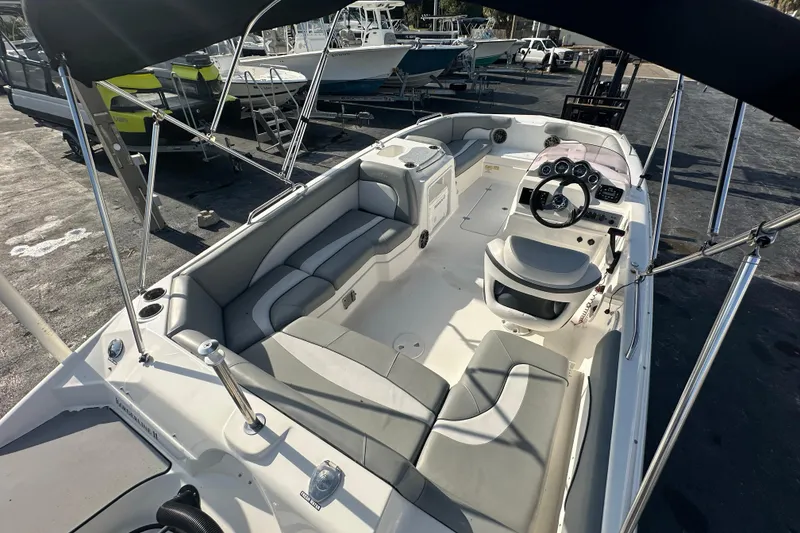 Slide: The Image of 2022 NauticStar 203 SC boat interior with seating and steering wheel, docked outdoors. - 7