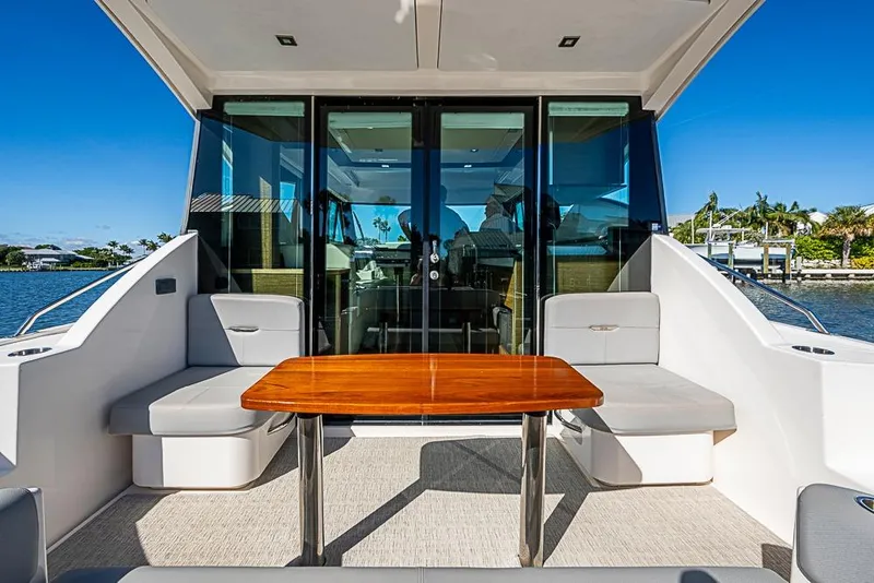 Slide: The Image of 2018 Tiara Yachts C39 Coupe, elegant outdoor seating with wooden table, scenic waterfront view. - 35