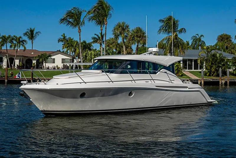 Slide: The Image of 2018 Tiara Yachts C39 Coupe cruising on a sunny day near palm-lined waterfront homes. - 7