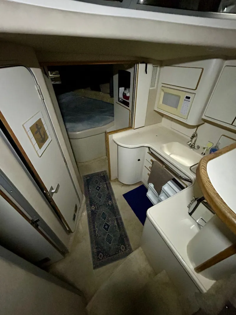 Slide: The Image of Interior of 1996 Sea Ray 370 Sedan Bridge, featuring kitchen and sleeping area. - 12
