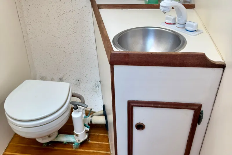 Slide: The Image of 1985 Cape Dory 28 Power Yacht bathroom with sink and toilet, featuring wood accents. - 14