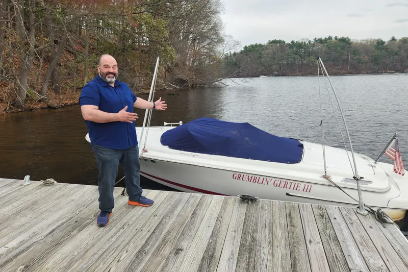 Slide: The Image of Man showcasing 2015 Chris-Craft Lancer 20 boat named "Grumblin' Gertie III" docked by a lake. - 2
