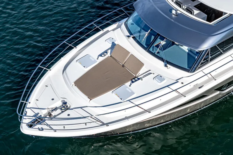 Slide: The Image of 2024 Riviera 465 SUV boat with sunbathing deck on calm water. - 12