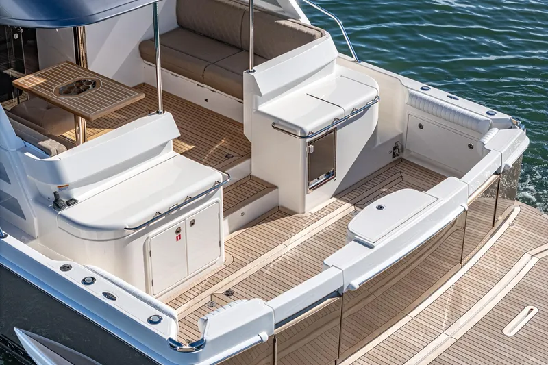 Slide: The Image of 2024 Riviera 465 SUV boat deck with seating and table, docked on water. - 18