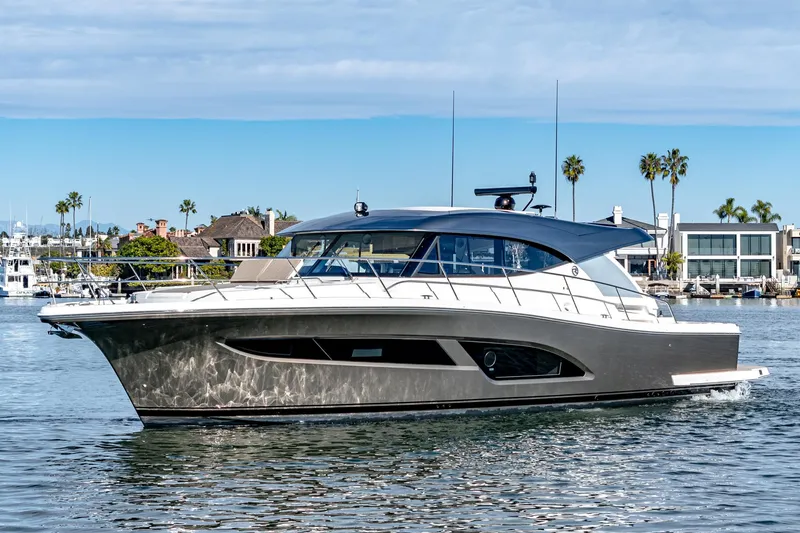 Slide: The Image of 2024 Riviera 465 SUV luxury yacht cruising in a scenic marina. - 2