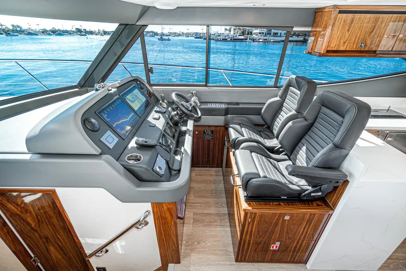 Slide: The Image of 2024 Riviera 465 SUV yacht cockpit with dual captain chairs and advanced navigation system. - 35