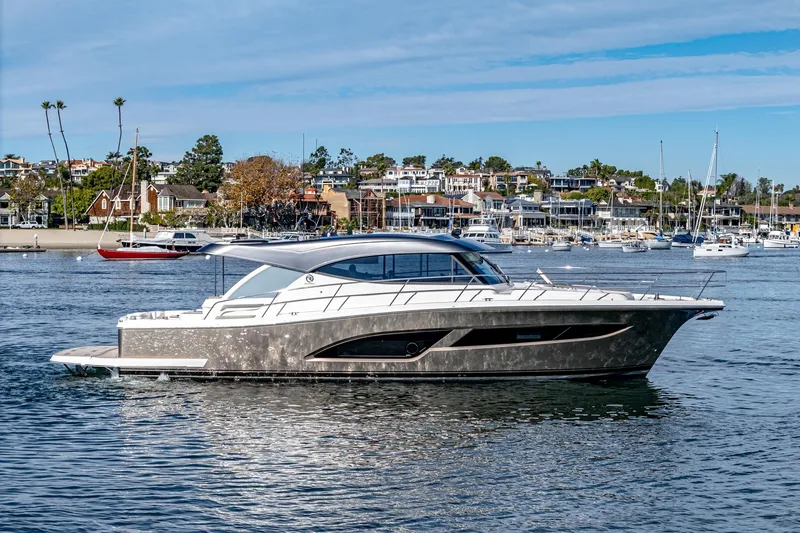 Slide: The Image of 2024 Riviera 465 SUV luxury yacht cruising in a scenic harbor. - 7