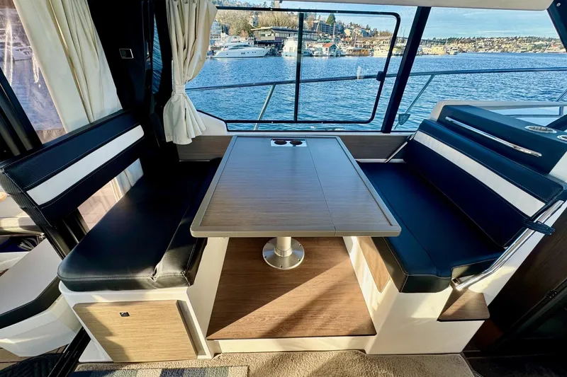 Slide: The Image of 2024 Jeanneau NC 1095 Coupe Series 2 interior dining area with waterfront view. - 10