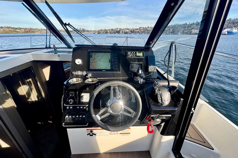 Slide: The Image of 2024 Jeanneau NC 1095 Coupe Series 2 helm with navigation equipment and scenic water view. - 12