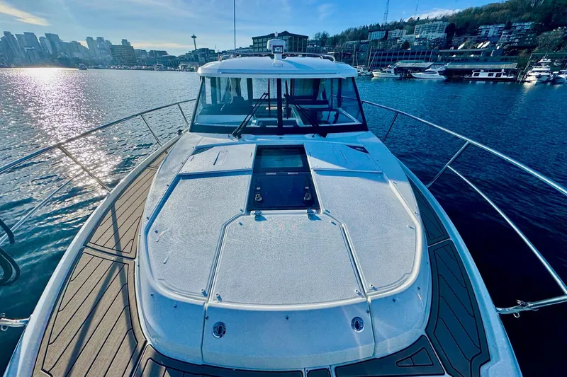 Slide: The Image of 2024 Jeanneau NC 1095 Coupe Series 2 on water, city skyline in background. - 13