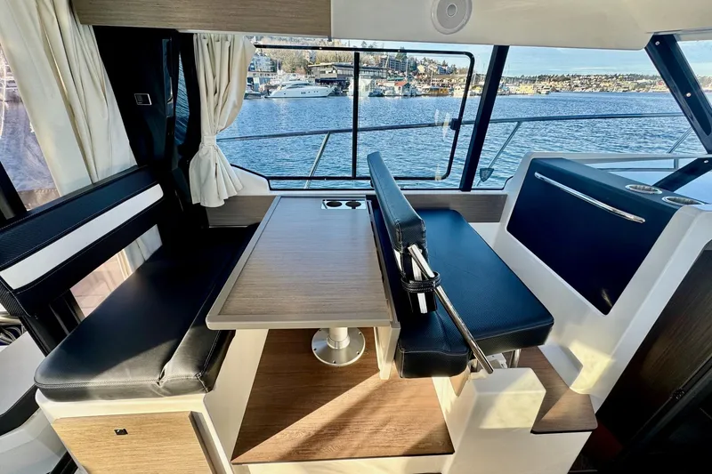 Slide: The Image of 2024 Jeanneau NC 1095 Coupe Series 2 interior with dining area and scenic window view. - 14