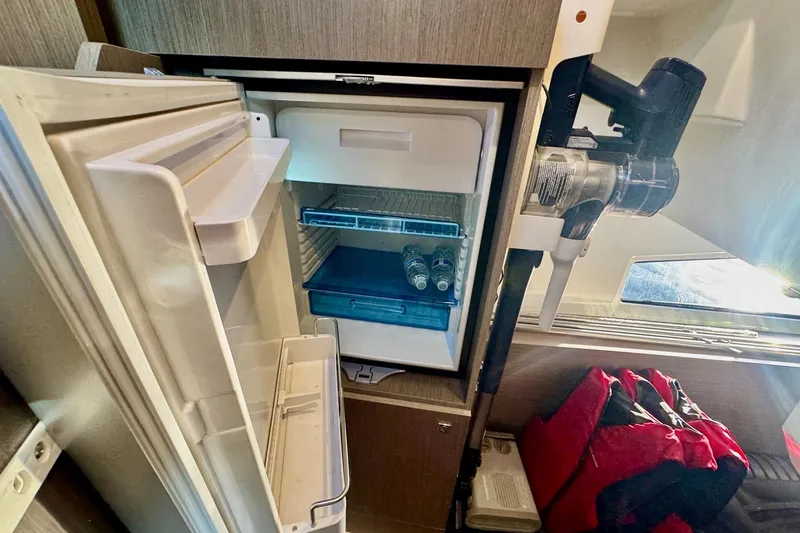 Slide: The Image of 2024 Jeanneau NC 1095 Coupe Series 2 interior fridge with open door and vacuum cleaner. - 19