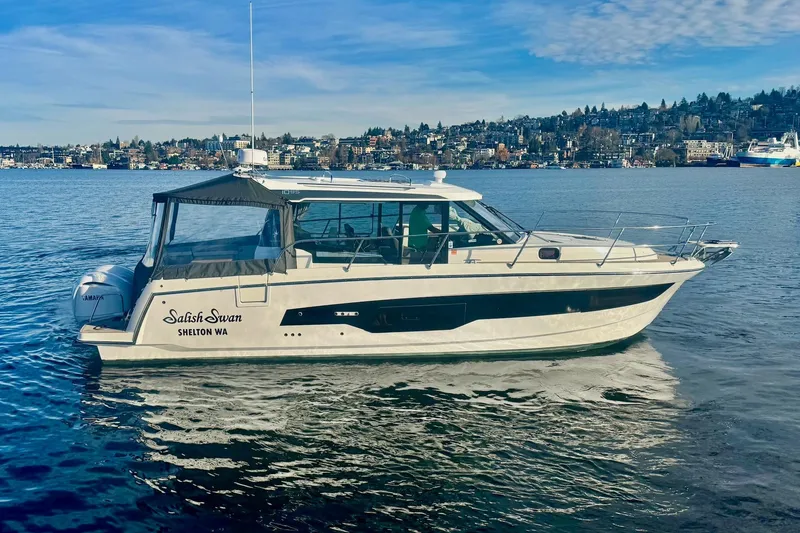 Slide: The Image of 2024 Jeanneau NC 1095 Coupe Series 2 boat on calm water, cityscape background. - 4