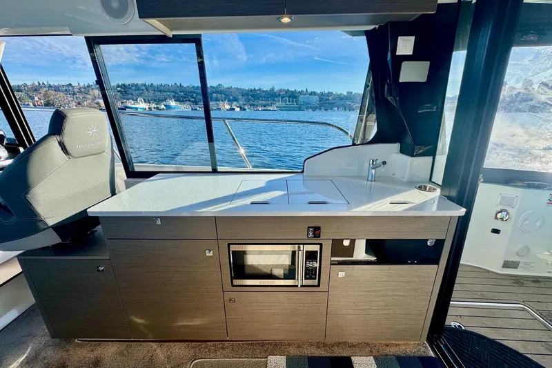 Slide: The Image of 2024 Jeanneau NC 1095 Coupe Series 2 interior with kitchenette and scenic water view. - 9