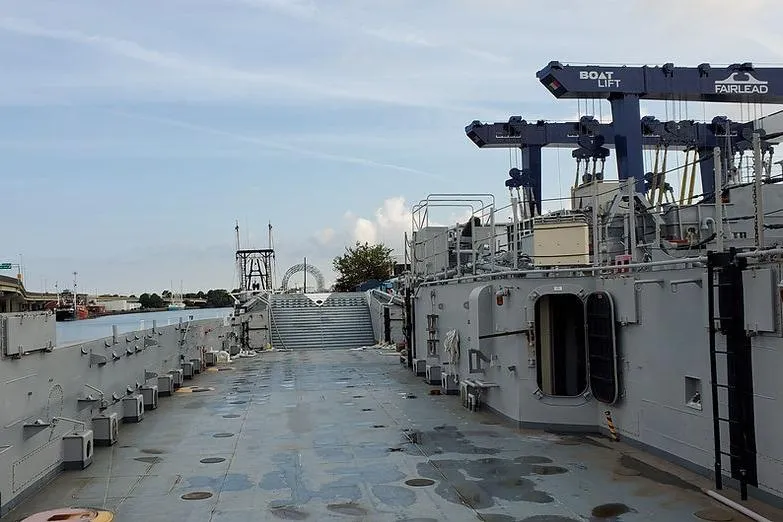 Slide: The Image of 1970 COMMERICAL BOAT LCU-135 deck with equipment and open doors, under a clear sky. - 1