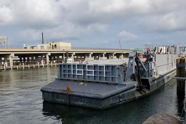 Slide: The Image of 1970 COMMERICAL BOAT LCU-135 docked at a harbor under cloudy skies. - 4