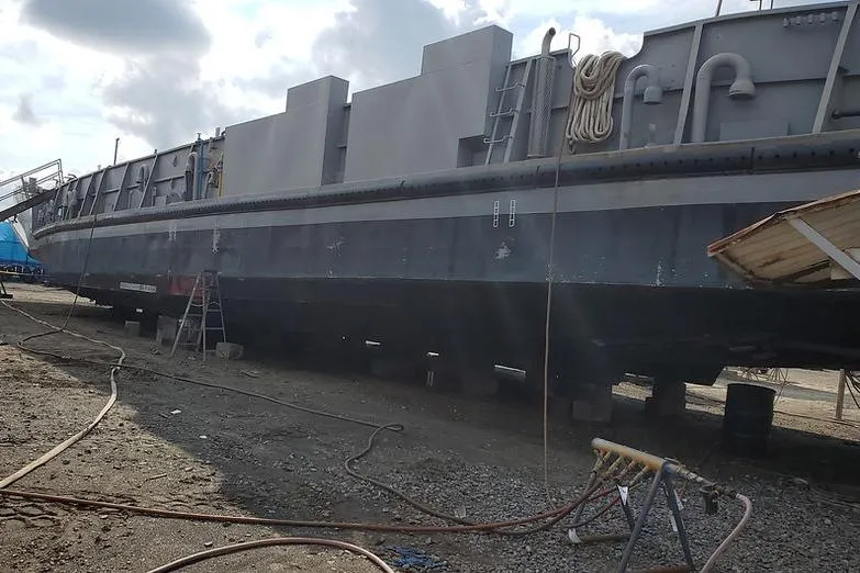 Slide: The Image of 1970 COMMERICAL BOAT LCU-135 on dry dock, undergoing maintenance with cloudy sky backdrop. - 6