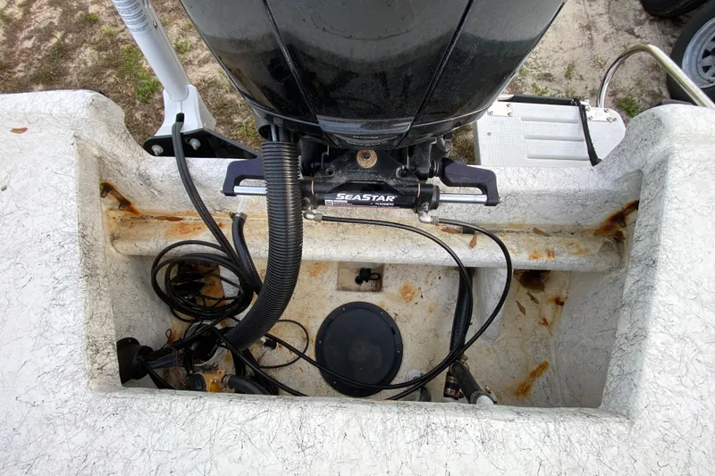 Slide: The Image of 2006 Mako 191 Inshore boat engine compartment with visible cables and rust. - 64