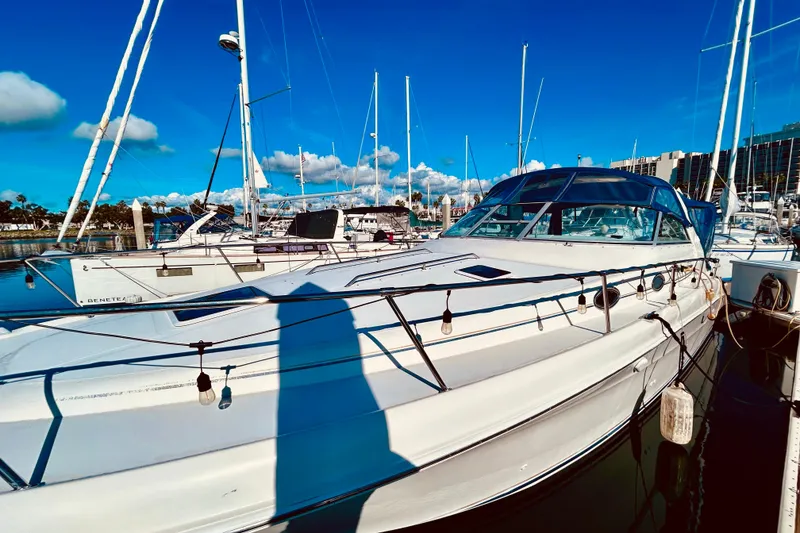 Slide: The Image of 1999 Sea Ray Sundancer 330 yacht docked in a marina under a clear blue sky. - 3