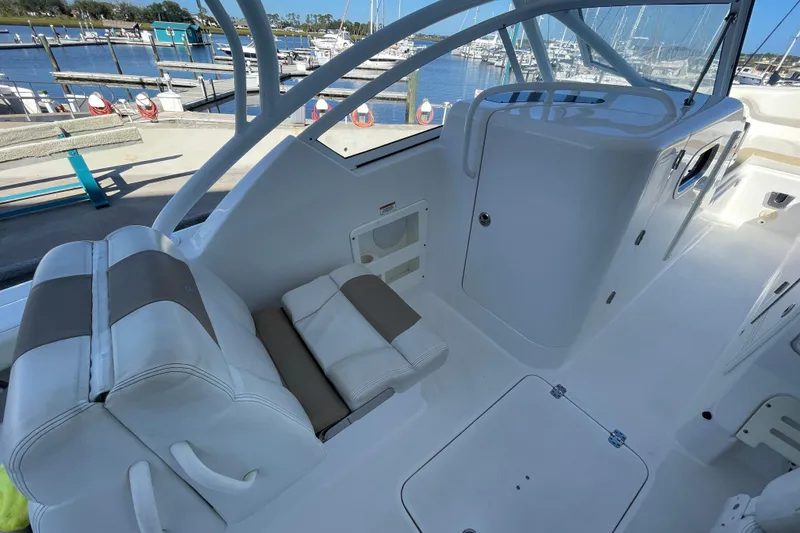 Slide: The Image of 2017 Edgewater 248CX Crossover boat interior with white seating and marina view. - 6