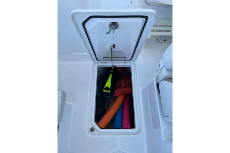 Slide: The Image of Open storage compartment on 2017 Edgewater 248CX Crossover boat with colorful pool noodles. - 7