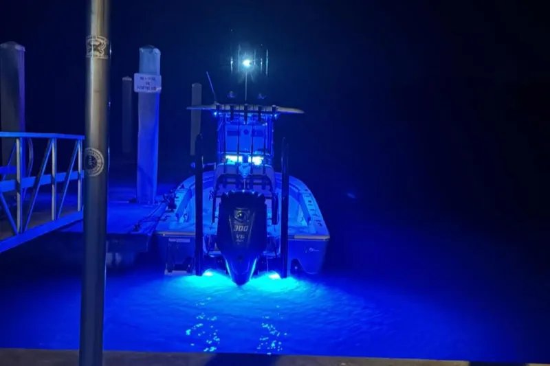 Slide: The Image of 2022 Sportsman Masters 247OE Bay Boat illuminated with blue lights at night. - 27