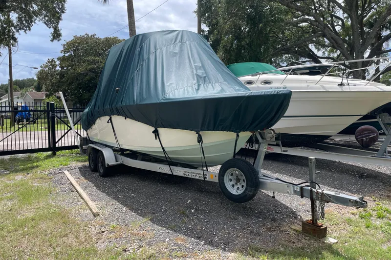 Slide: The Image of 2021 Sea Pro 219 Center Console boat covered on a trailer in a parking area. - 21