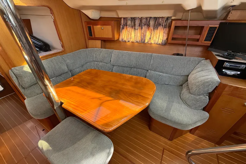 Slide: The Image of Cozy interior of 1999 Hunter Passage 420 yacht with wooden table and cushioned seating. - 24