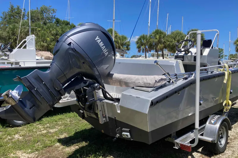 Slide: The Image of 2026 Gospel Boat Landing Craft with Yamaha engine, parked on a trailer, surrounded by palm trees. - 3