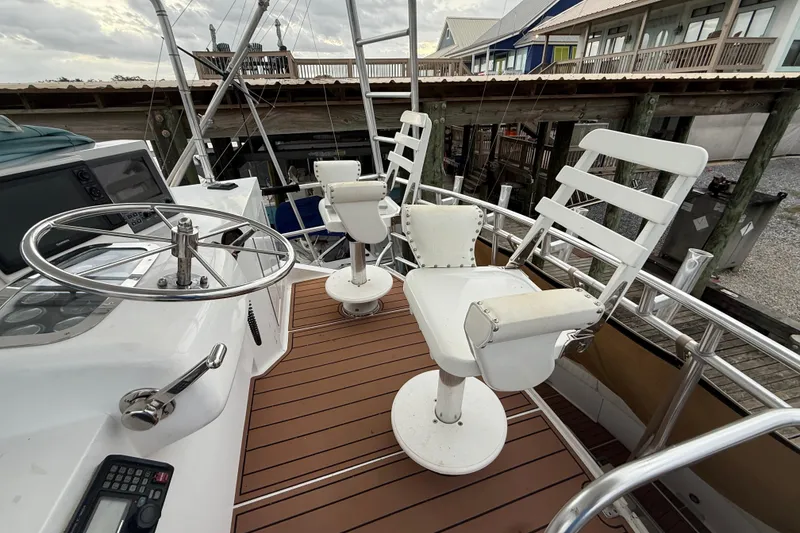 Slide: The Image of 1988 Cheoy Lee 58 Convertible yacht helm with white captain chairs and steering wheel. - 77