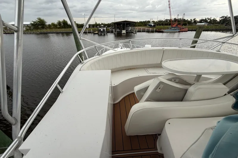 Slide: The Image of 1988 Cheoy Lee 58 Convertible yacht deck with seating and table, docked by calm waters. - 78