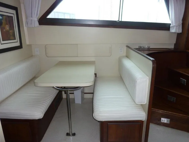 Slide: The Image of 1987 Hatteras Flybridge interior with white upholstered seating and dining table. - 15