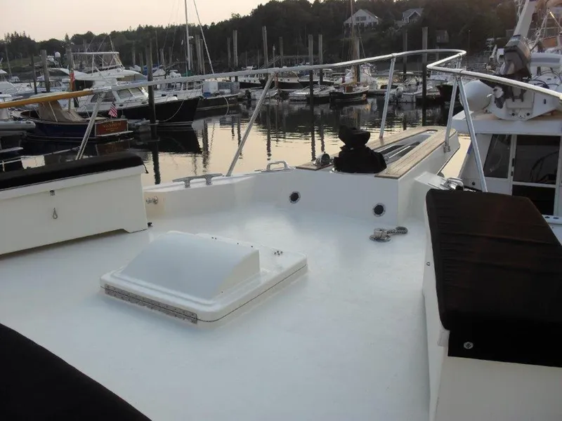 Slide: The Image of 1987 Hatteras Flybridge yacht deck at marina, featuring seating and mooring equipment. - 23