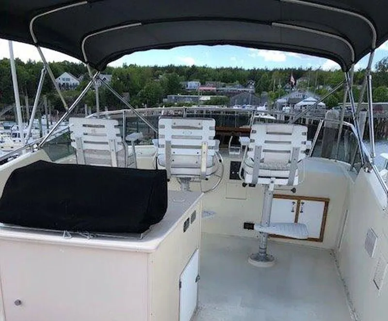 Slide: The Image of 1987 Hatteras Flybridge with seating, canopy, and marina view in the background. - 27