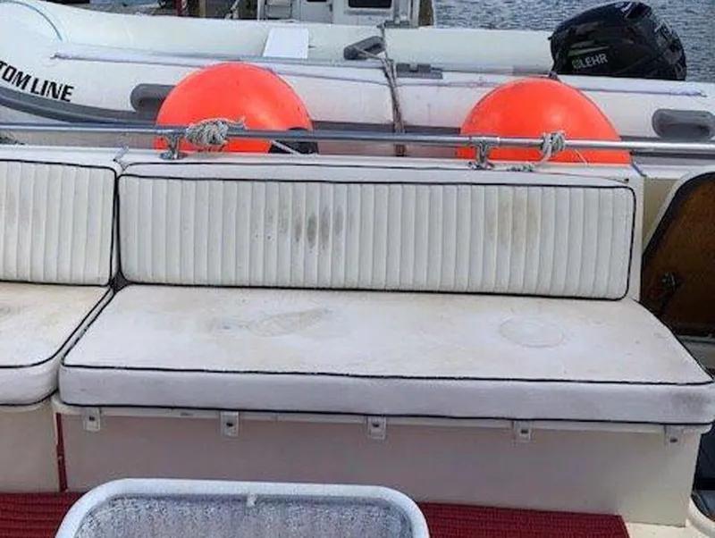 Slide: The Image of 1987 Hatteras Flybridge boat seating area with white cushions and orange buoys in the background. - 29