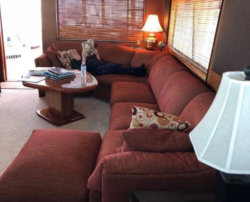 Slide: The Image of Cozy 1987 Hatteras Flybridge interior with red sectional sofa and warm lighting. - 3
