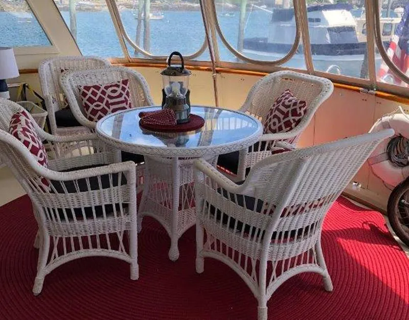 Slide: The Image of 1987 Hatteras Flybridge interior with wicker furniture and red accents, overlooking marina. - 34
