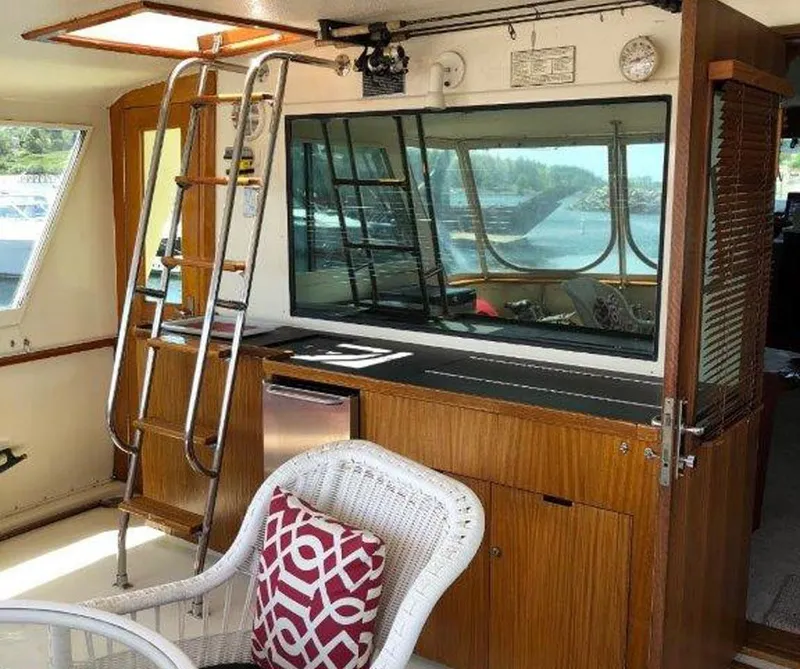 Slide: The Image of 1987 Hatteras Flybridge interior with ladder, wicker chair, and window view. - 35