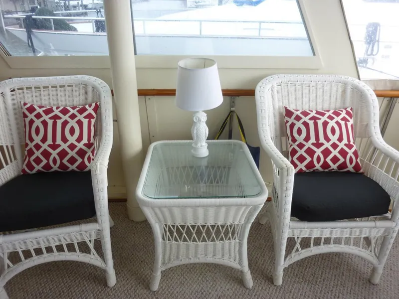 Slide: The Image of White wicker chairs and table with red patterned cushions on a 1987 Hatteras Flybridge. - 38