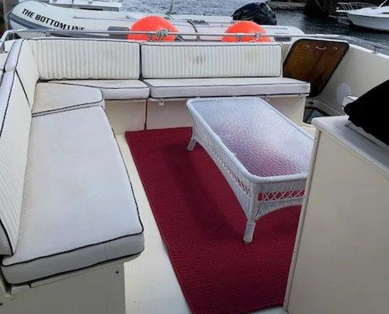 Slide: The Image of 1987 Hatteras Flybridge yacht interior with white seating, glass table, and red rug. - 39