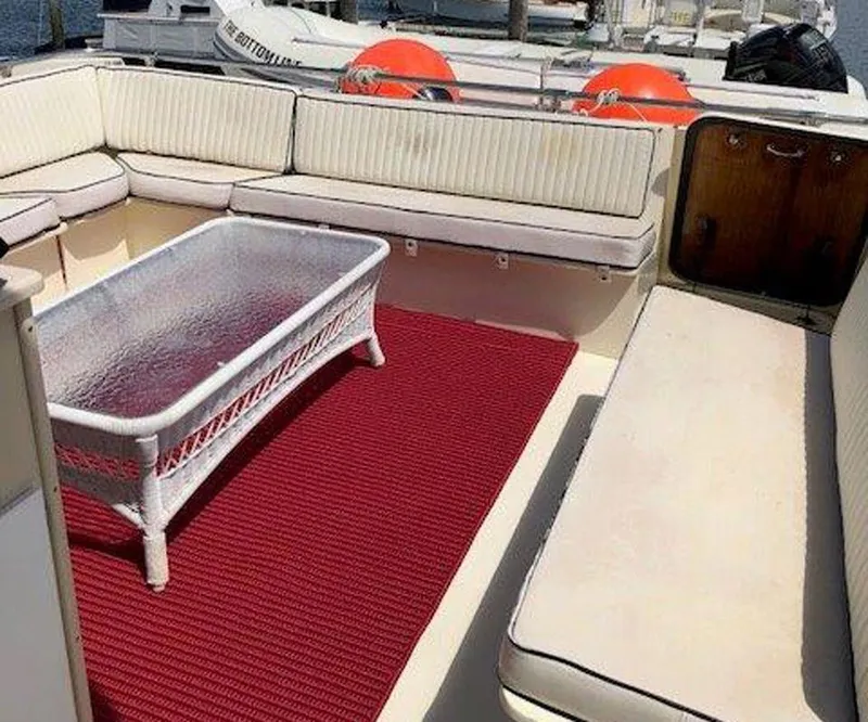 Slide: The Image of 1987 Hatteras Flybridge yacht interior with cushioned seating, glass table, and red carpet. - 40