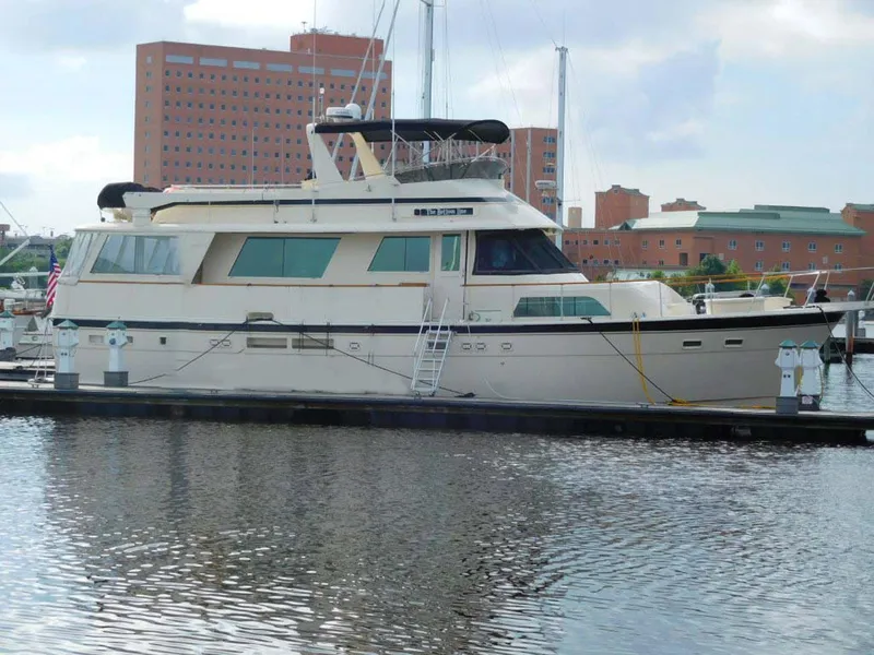 Slide: The Image of 1987 Hatteras Flybridge yacht docked at a marina with cityscape background. - 47