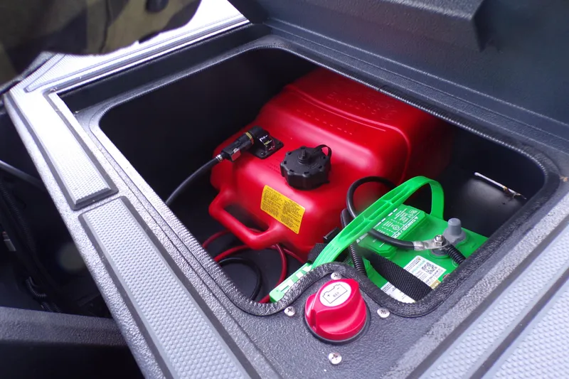 Slide: The Image of Open storage compartment in 2026 Xpress Bayou 180 with red fuel tank and green battery. - 18