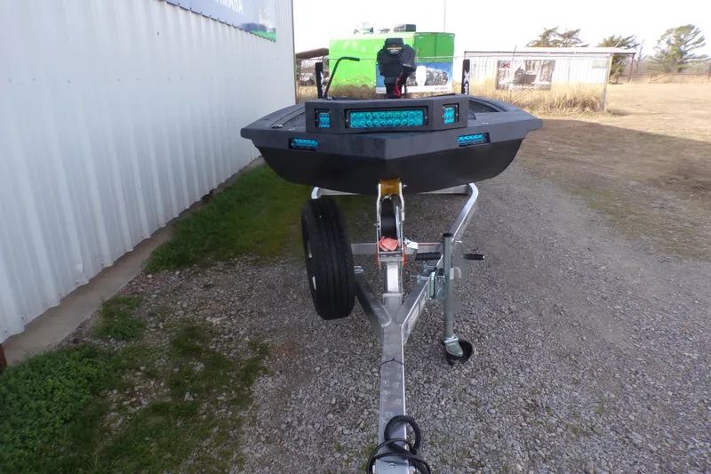 Slide: The Image of 2026 Xpress Bayou 180 boat on trailer, parked outdoors near a metal building. - 4